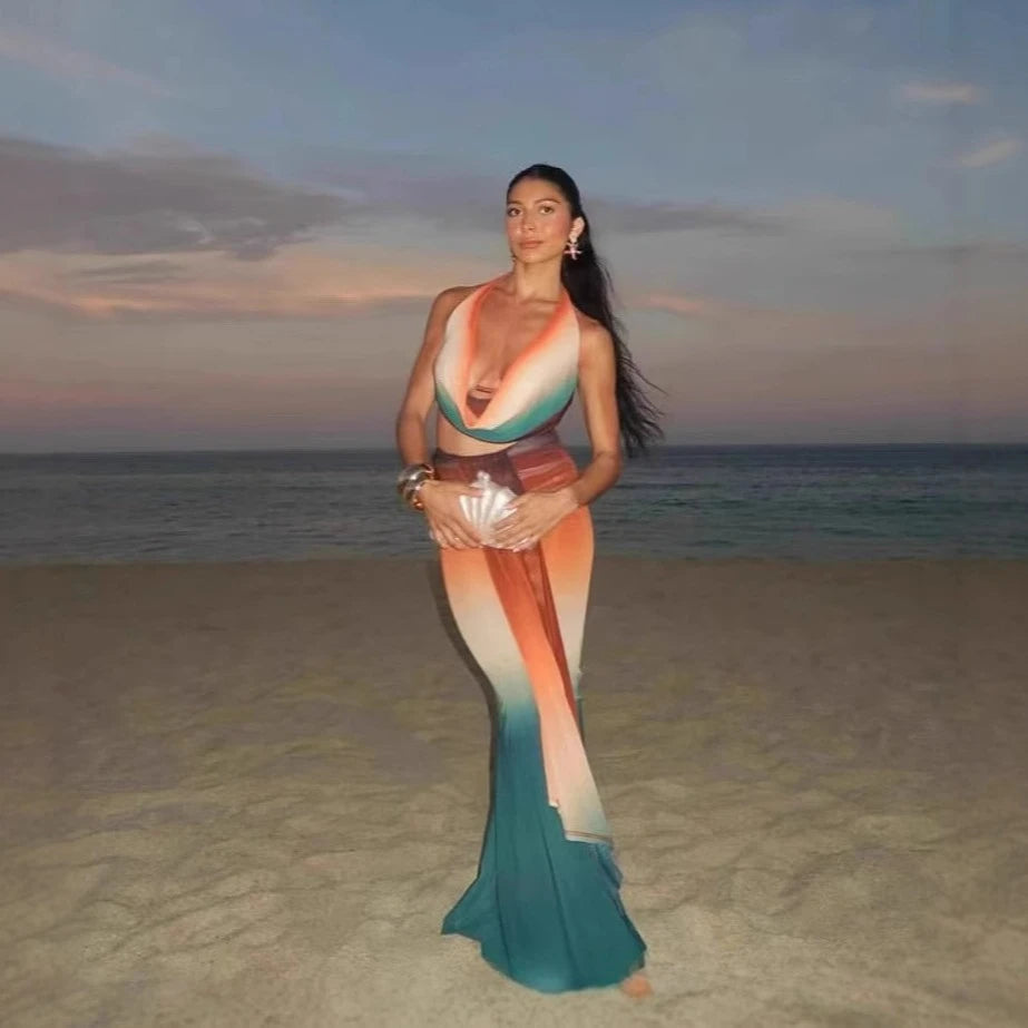 Woman in a colorful dress standing on a beach at sunset
