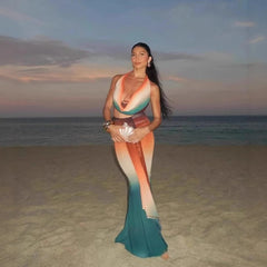 Woman in a colorful dress standing on a beach at sunset