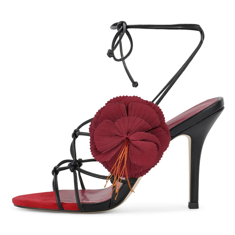 Red and black stiletto lace-up sandals with large floral embellishment
