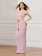 Woman wearing a pink two-piece outfit against a white wall.