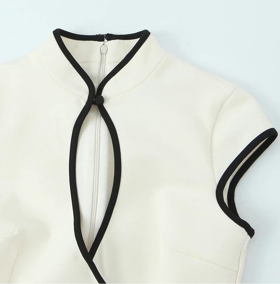 White sleeveless top with black trim on a light gray background