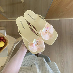 Beige sandals with floral decorations held by a person indoors.