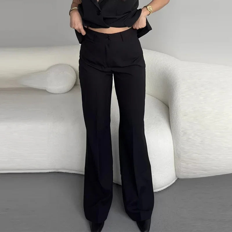 Person wearing black high-waisted pants standing in a minimalistic room with a white sofa.