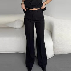 Person wearing black high-waisted pants standing in a minimalistic room with a white sofa.