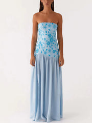 Woman wearing a strapless blue floral dress on a white background