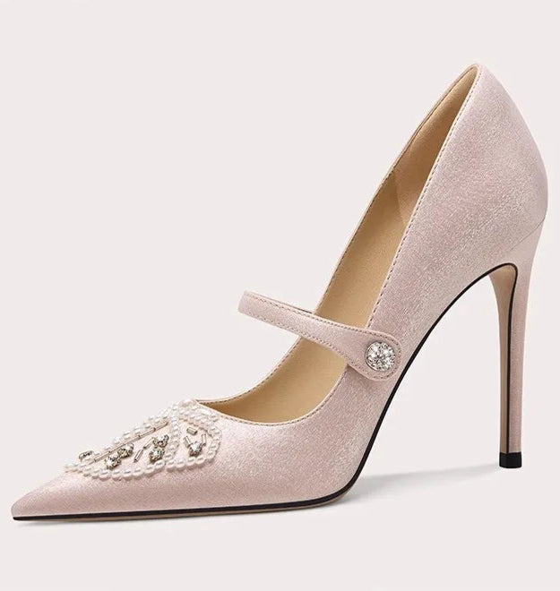 Pink high-heeled shoe with decorative strap on a light gray background