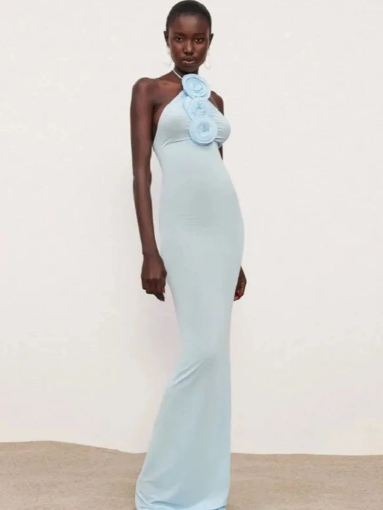 Woman wearing a light blue evening gown with a floral detail on a plain background