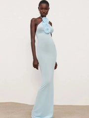 Woman wearing a light blue evening gown with a floral detail on a plain background