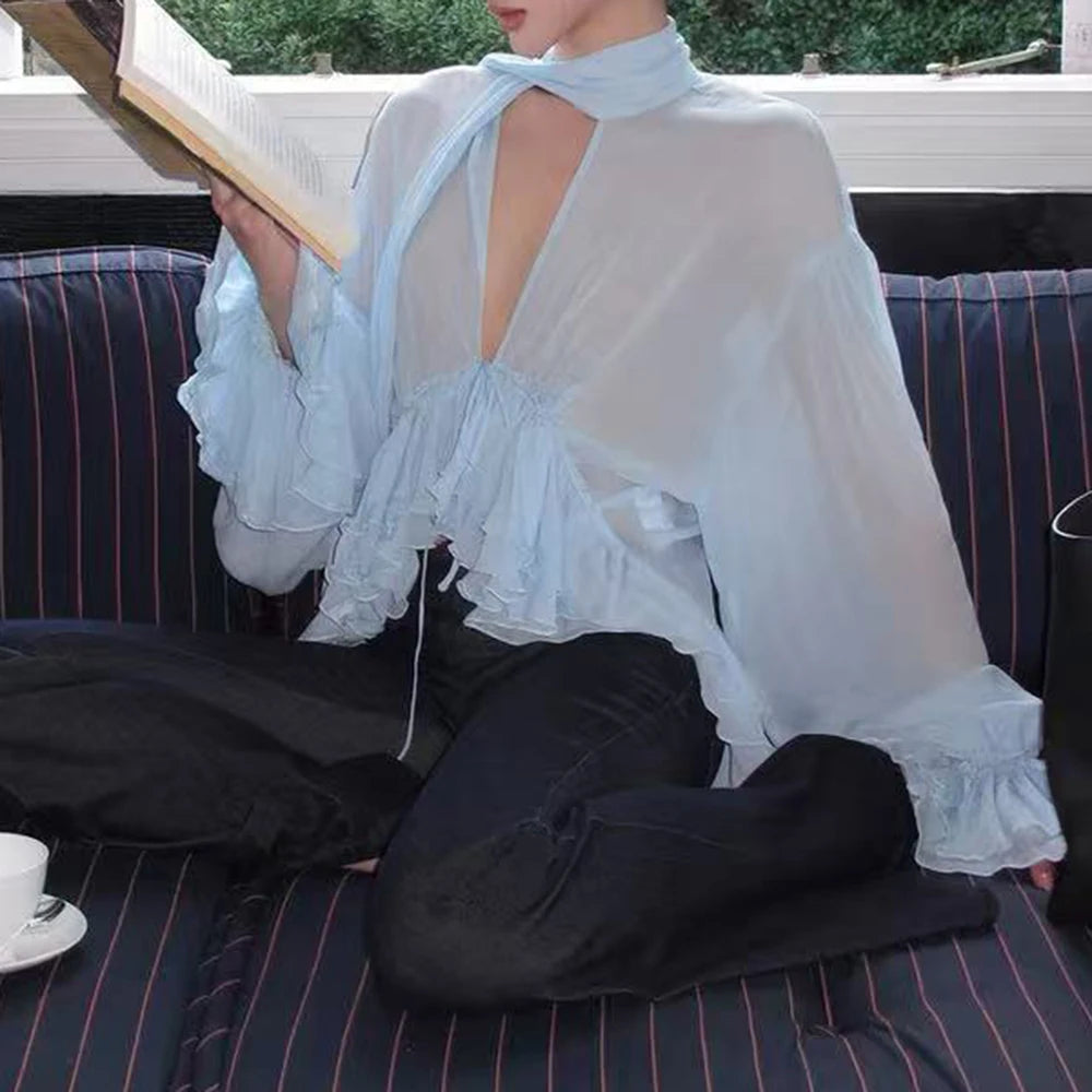 Sheer ruffled halter blouse on a woman sitting on a couch, holding a book.