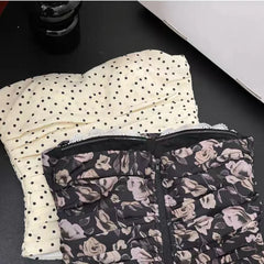 Two folded garments, one with polka dot pattern and the other with floral pattern, on a dark surface.