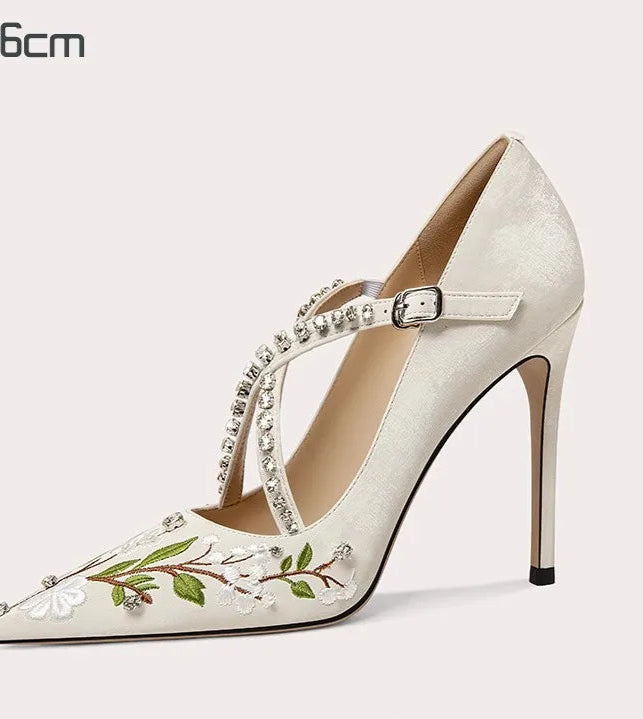High-heeled shoe with floral design and embellishments on a white background
