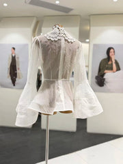 White lace dress on a mannequin in a display setting with blurred background