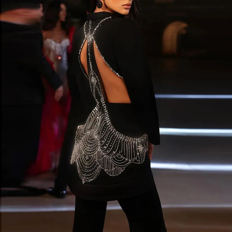 Person wearing a black outfit with intricate silver detailing on a blurred background