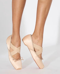 Beige ballet shoes worn by a person on a light gray background