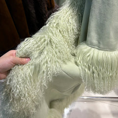 Close-up of a fluffy white garment with a person's hand touching it.