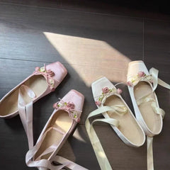 White ballet flats with floral embellishments and ribbon ties