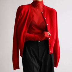 Red cardigan over a red shirt with black pants on a light gray background