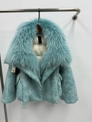 Teal coat with fur hood on a rack against a white background