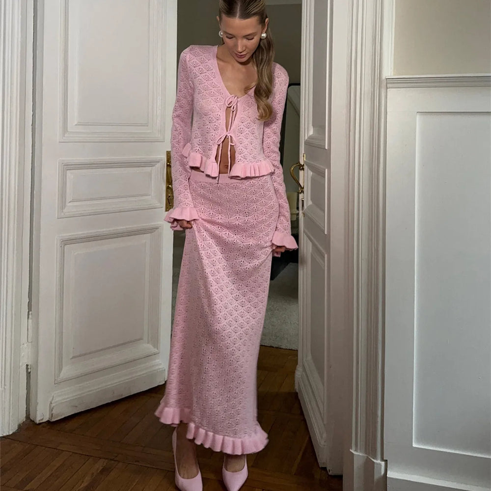 Woman in a pink outfit standing in a doorway.