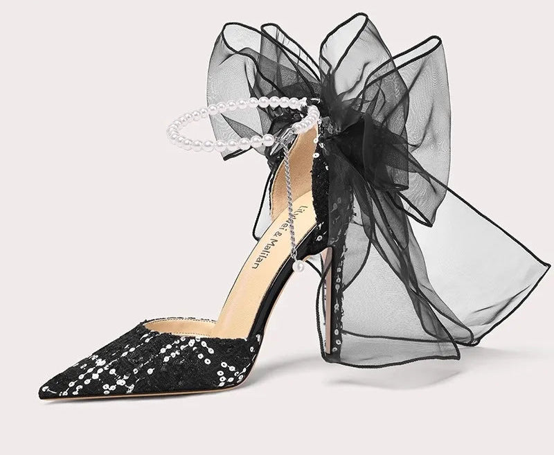 Black high-heeled shoe with sheer bow on a white background