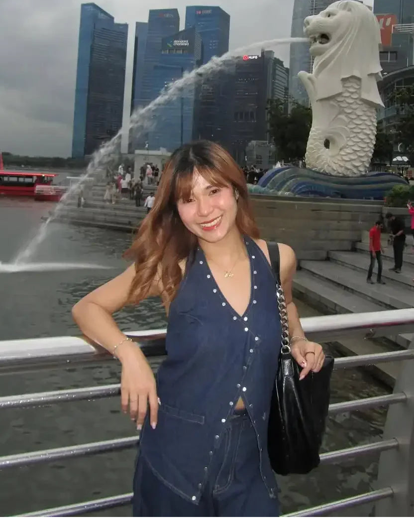 Woman posing in front of the Merlion statue in Singapore with city skyline in the background