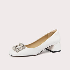 White shoe with a decorative buckle on a light gray background