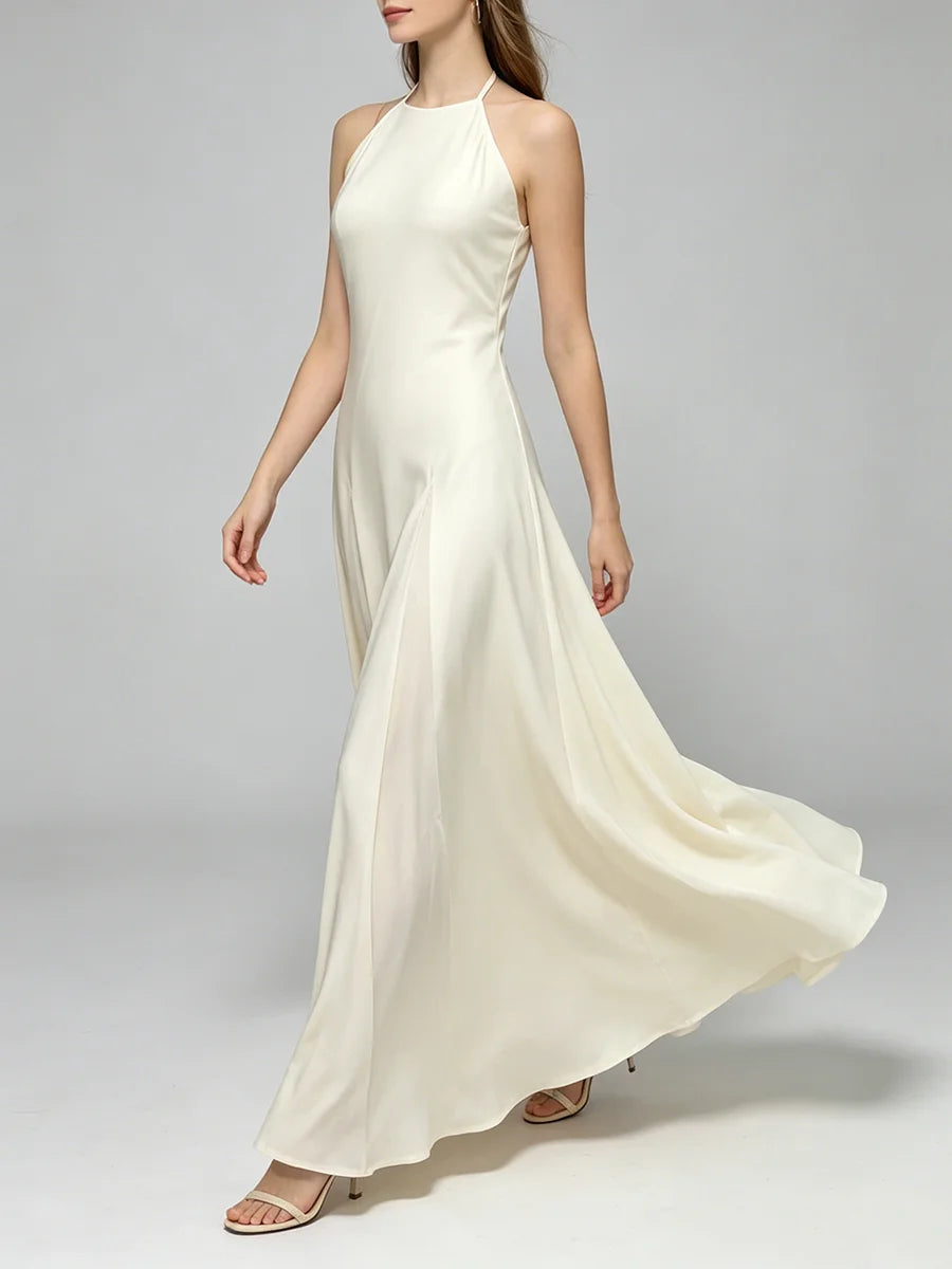 Model wearing a flowing halter neck a-line maxi dress with a pleated skirt.