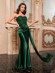 Woman in a green evening gown with a long train in an elegant room.