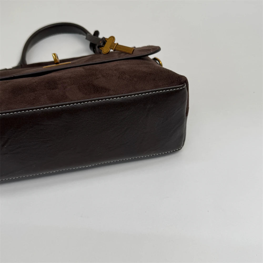 Brown leather handbag with gold accents on a white background