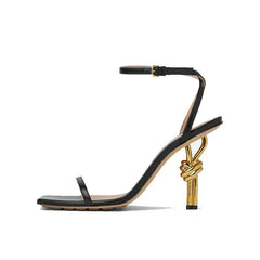 Black sandal with gold heel on a white background