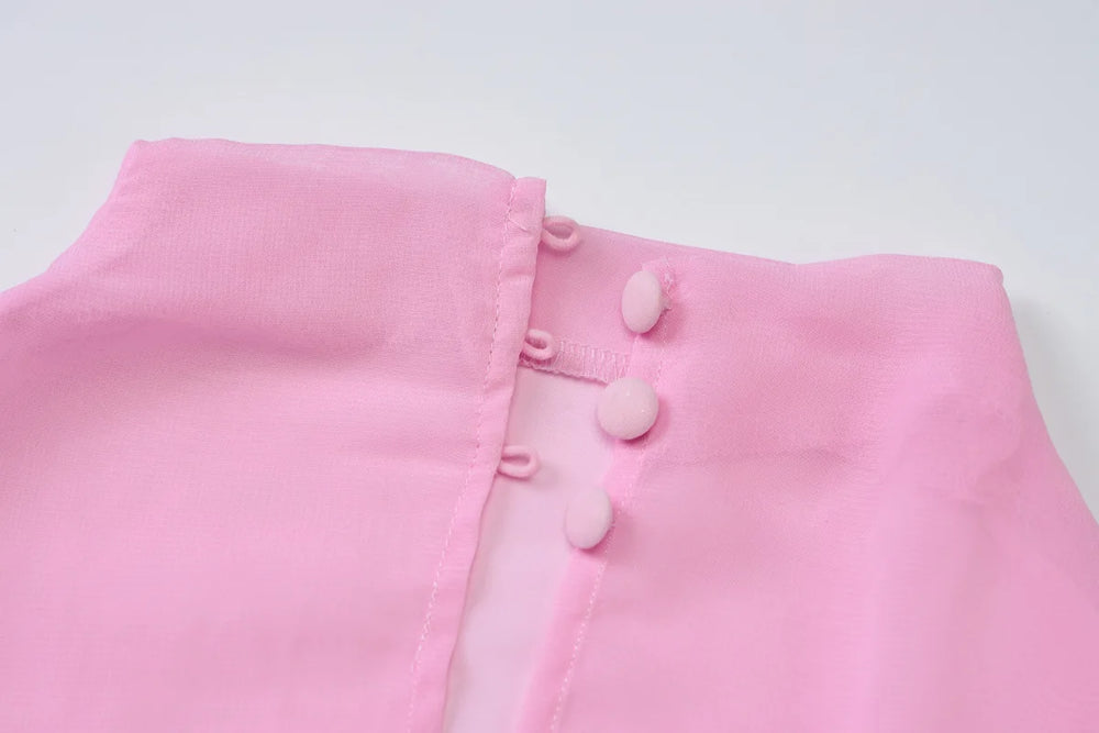 Close-up of a pink garment with buttons on a light gray background