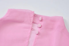 Close-up of a pink garment with buttons on a light gray background