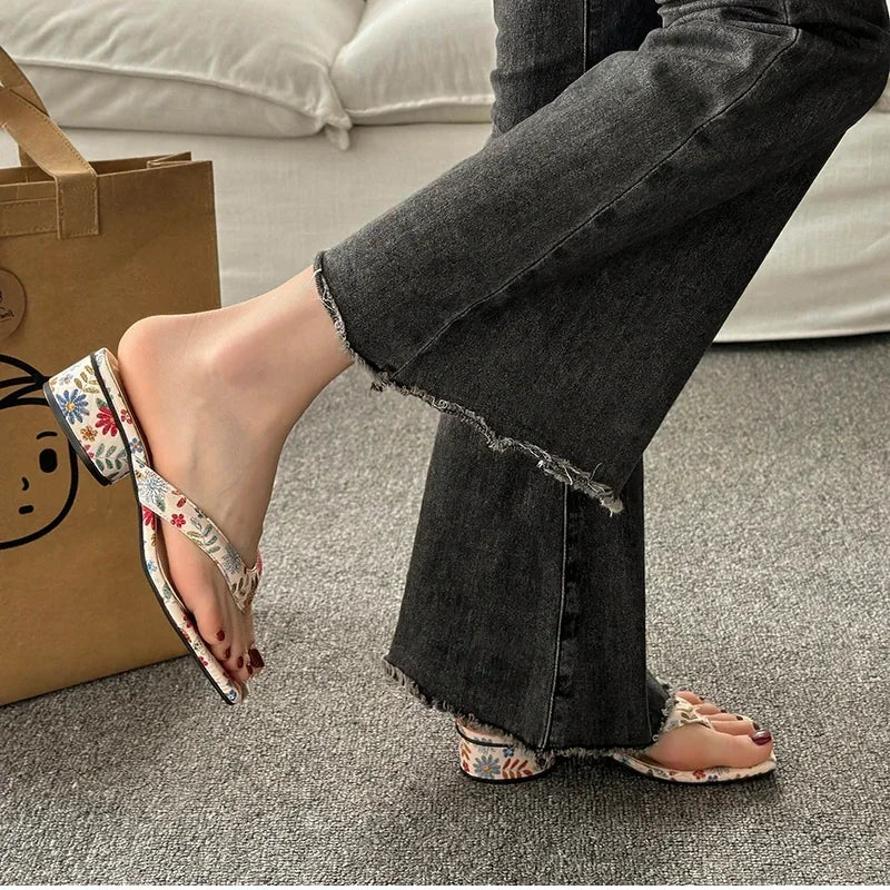 Person wearing floral sandals with black jeans on a carpeted floor.