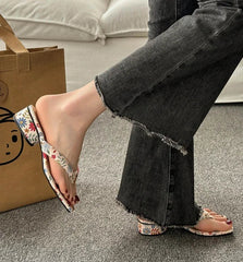 Person wearing floral sandals with black jeans on a carpeted floor.