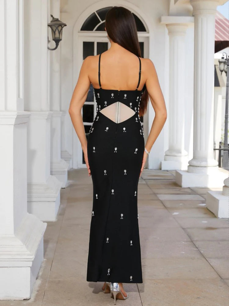 Woman wearing a black evening gown with cut-out design in an outdoor setting.