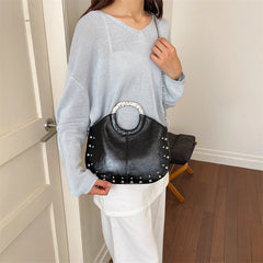 Black studded faux leather hobo bag with metal hoop handle and chain strap.