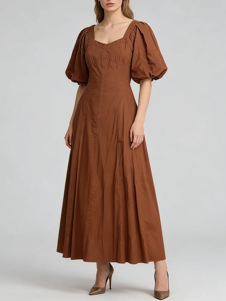 Woman wearing a brown dress with puff sleeves on a white background