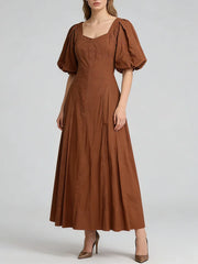Woman wearing a brown dress with puff sleeves on a white background