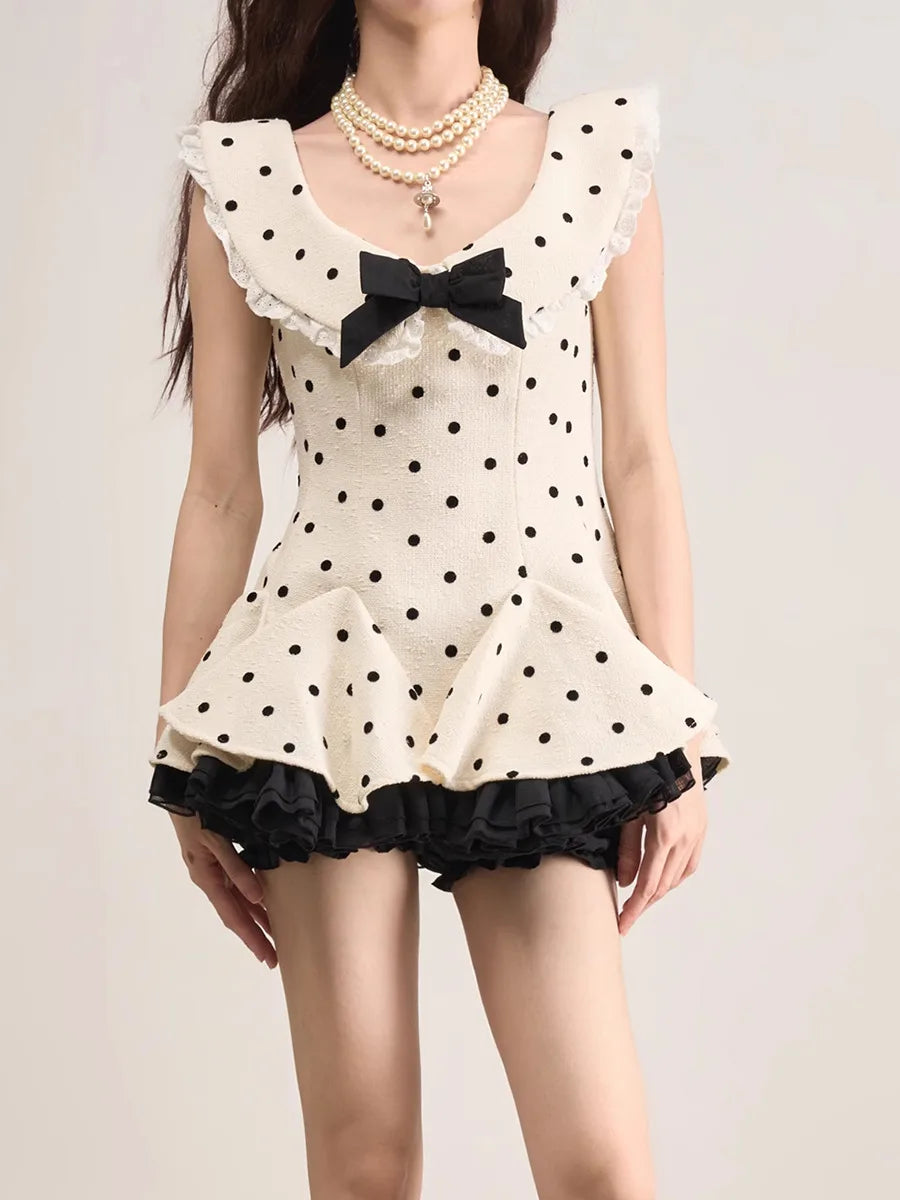 Woman wearing a polka dot dress with a black bow on a plain background