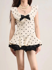 Woman wearing a polka dot dress with a black bow on a plain background