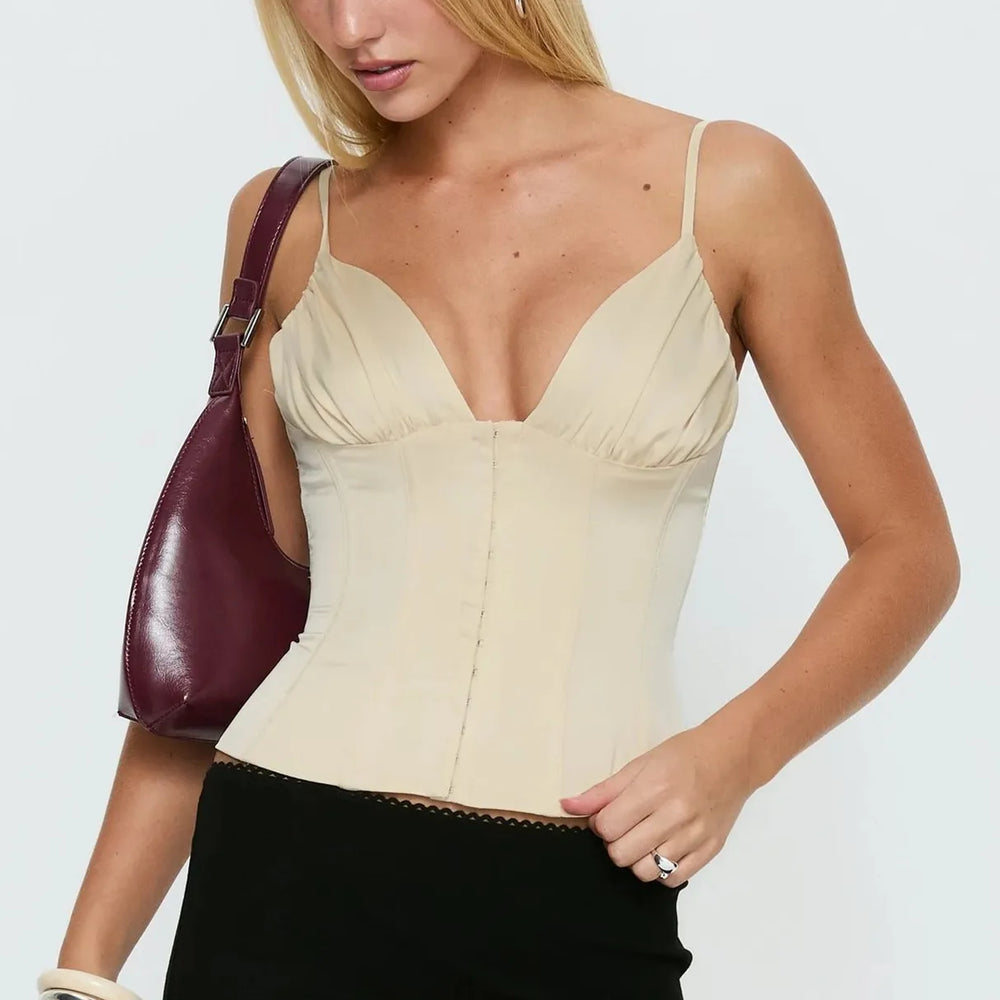 Woman wearing a beige corset top with a plain background