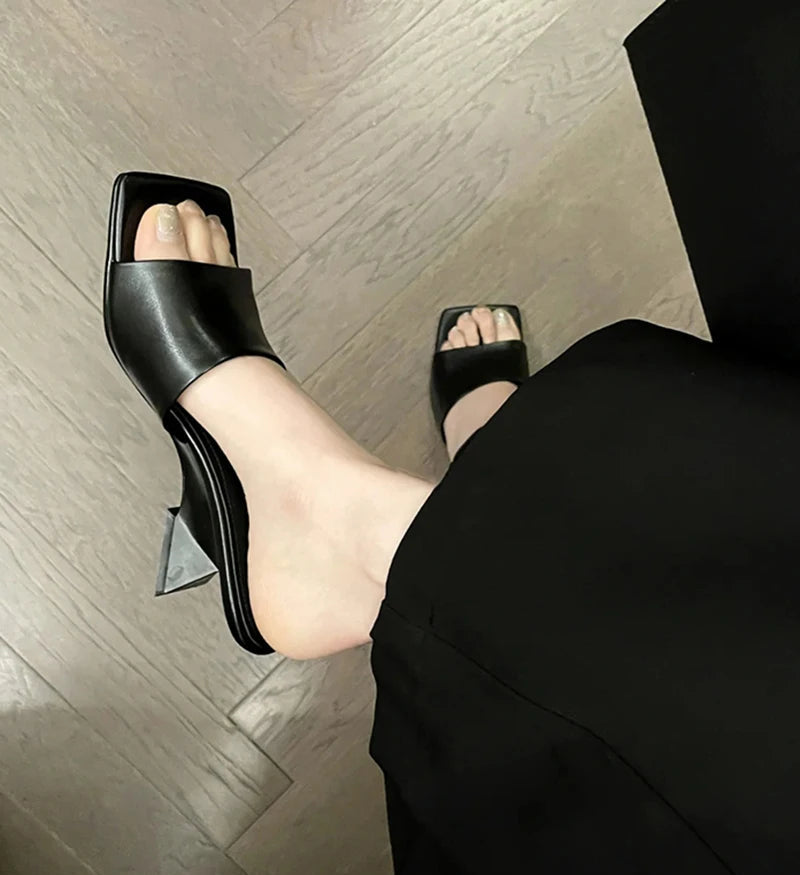 Black high-heeled shoes worn on a wooden floor