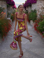Woman in a colorful dress walking through a flower-lined path.