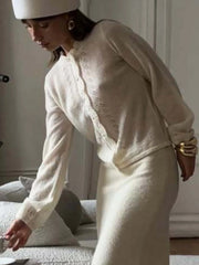Woman in a white outfit with gold accessories in a room setting