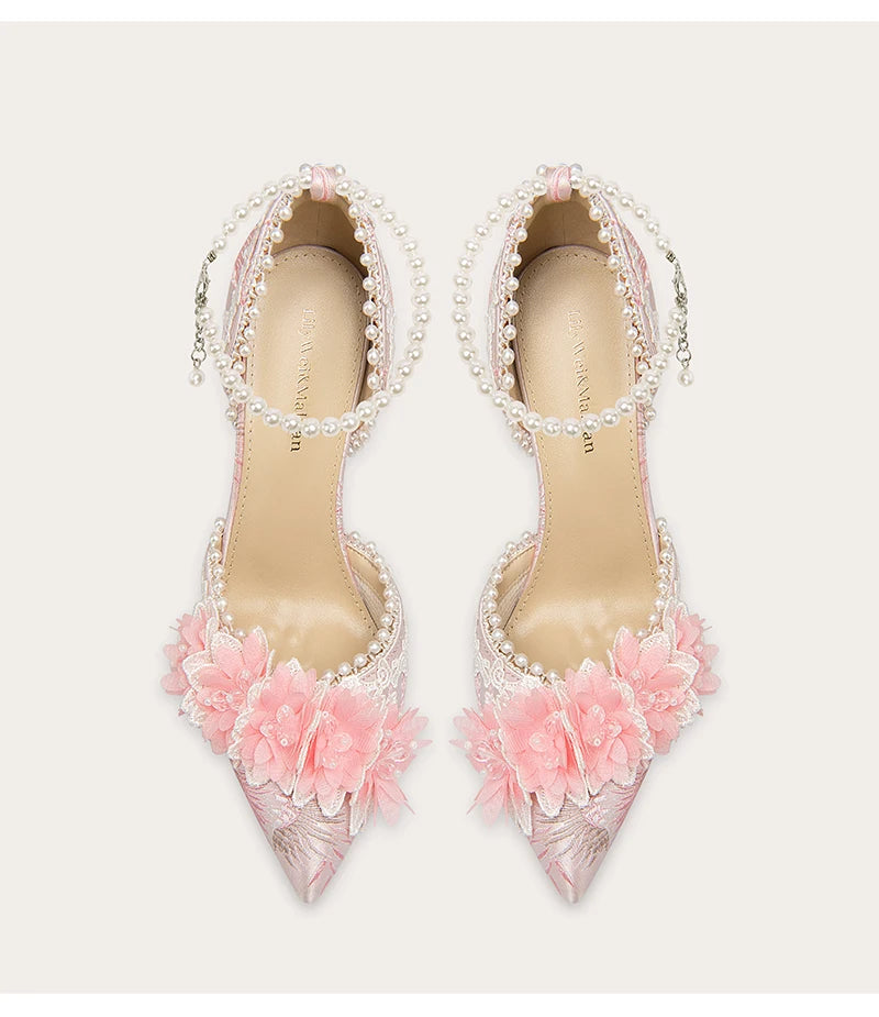 Pair of high-heeled shoes with floral and pearl details on a light background