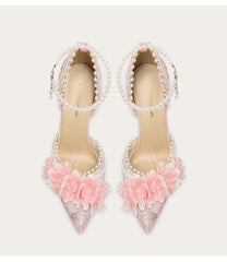 Pair of high-heeled shoes with floral and pearl details on a light background