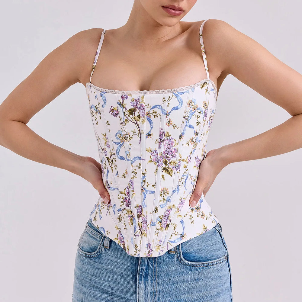 Woman wearing a floral corset top and jeans on a plain background