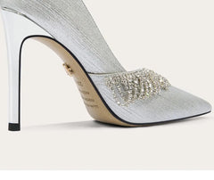 Silver high-heeled shoe with embellishments on a white background