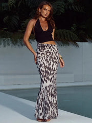Woman wearing a black top and leopard print skirt by a pool