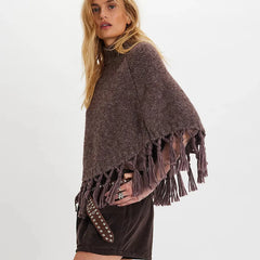 Woman wearing a brown poncho with fringe on a white background